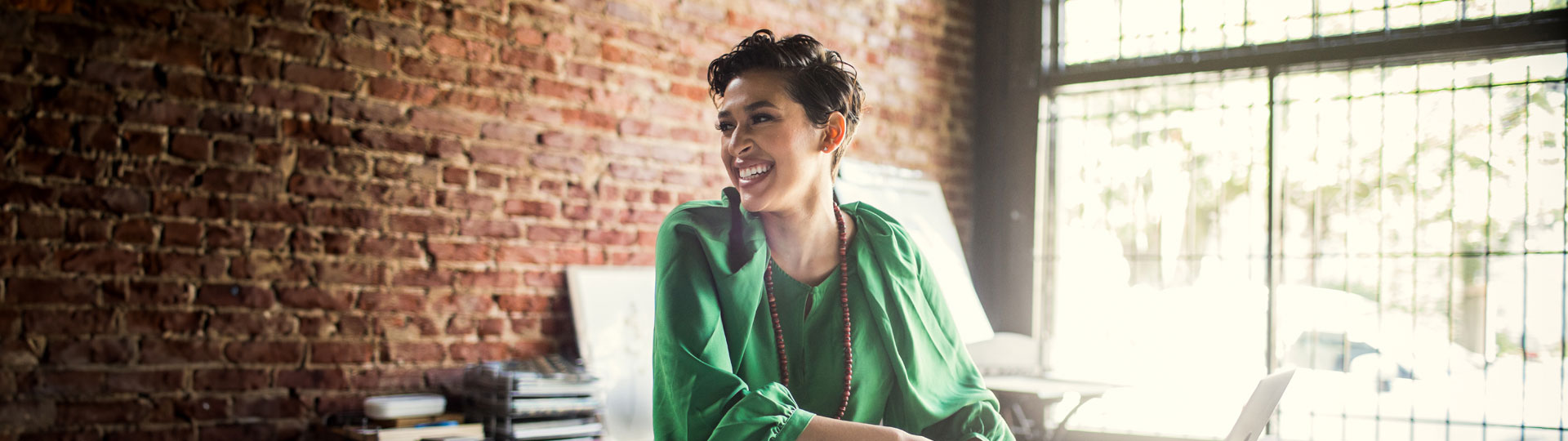 Woman smiling is sitting at her desk in a homely office