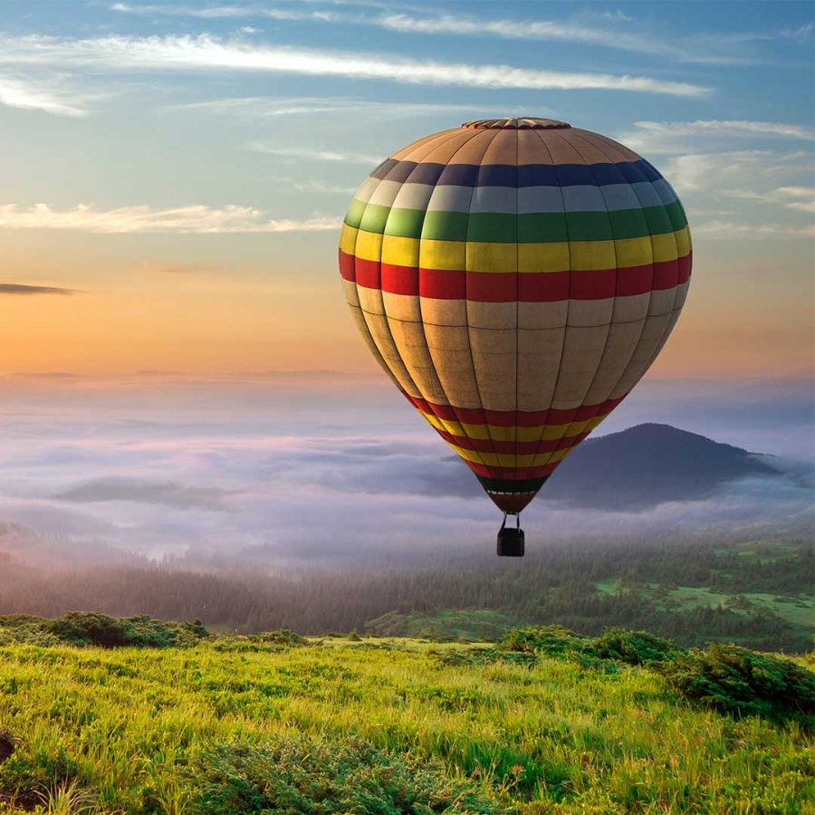 A hot air balloon over a grassy hill