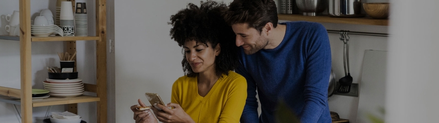 Couple staring at phone in the kitchen of their home